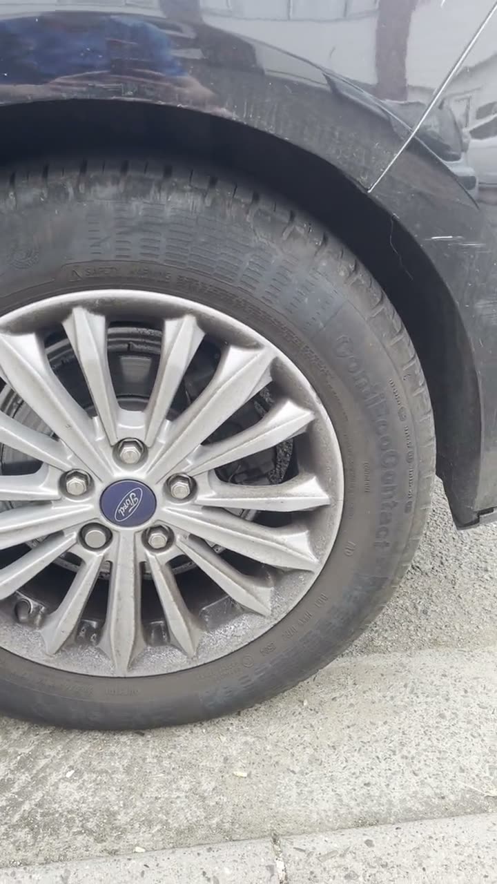 Silver Ford alloy wheel dulled with brake dust and road grime before cleaning