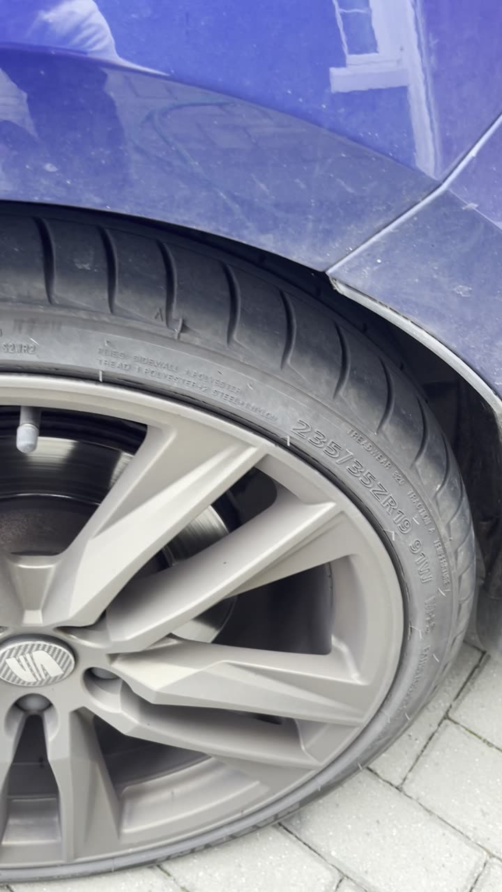 Dull, brake-dust-covered bronze alloy wheel on a blue Cupra before cleaning